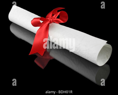 Diploma with a red silk ribbon, isolated on black background. Stock Photo