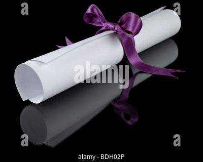 Diploma with a violet silk ribbon, isolated on black background. Stock Photo