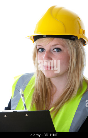 young 20 year old blonde woman wearing yellow hard hat and high vis vest writing on a clipboard with eye contact Stock Photo