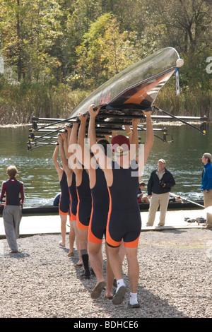 Members of the men's crew team at Hobart College carry their 8 man shell above their heads toward the water at the Hobart Crew R Stock Photo