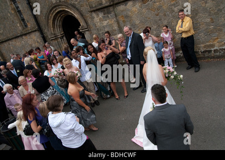 bride and groom and guests outside church Stock Photo