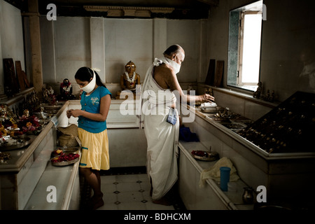 A teenage girl and an old man worship at a Jain temple. Stock Photo