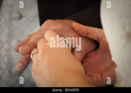 exchanging wedding rings, bride putting ring on groom Stock Photo