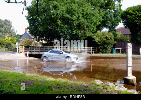 A car creating a splash as it drives through a ford Stock Photo