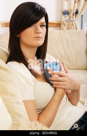 Pretty dark haired woman sitting at home holding a coffee cup Stock Photo