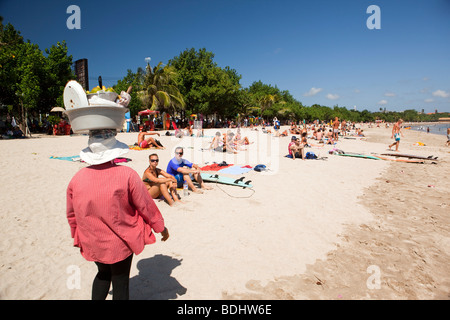 Indonesia, Bali, Kuta, beach, fruit vendor approaching sunbathing holidaymakers Stock Photo