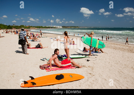 Indonesia, Bali, Kuta, beach, surfers resting on sand at waters edge Stock Photo