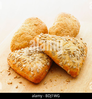 Fresh rustic wholemeal bread rolls on a bread board. Stock Photo