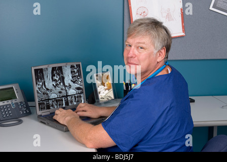 A doctor reviews an MRI on his laptop. Good for using technology to review imagery as opposed to hard film MRI's. Stock Photo