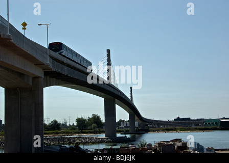 New Canada Line light rapid transit commuter train crossing cable stay suspension bridge over Fraser River Stock Photo