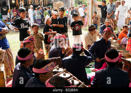 Indonesia, Bali, Tirta Gangga, young boys watching gamelan orchestra playing in local temple funeral ceremony Stock Photo