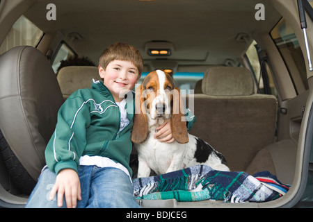 Boy and Basset Hound in Back of SUV Stock Photo