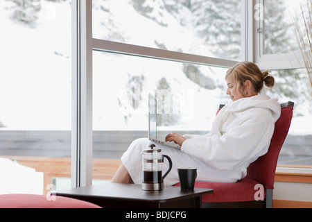 Woman Sitting by Window Using Laptop Computer Stock Photo