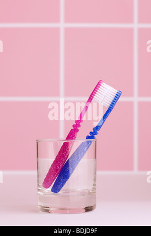 Two Toothbrushes in a Glass in Washroom Stock Photo