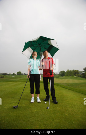 Father and Daughter on the Golf COurse Holding a Large Umbrella Stock Photo