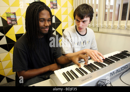 Two students learning playing keyboards in a recording suite. Stock Photo