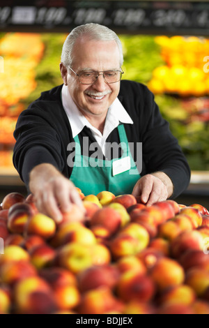 Grocery Clerk Arranging Peaches in Produce Aisle Stock Photo