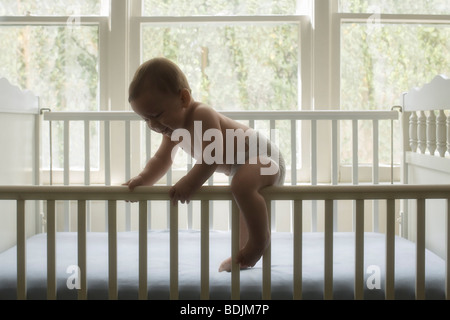 Baby Boy Climbing Out of Crib Stock Photo