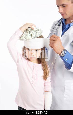 Doctor Wrapping Bandage Around Girl's Head Stock Photo