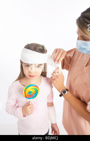 Nurse Wrapping Bandage Around Girl's Head Stock Photo