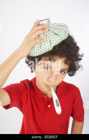 Boy With a Thermometer in His Mouth and an Ice Pack on His Head Stock Photo