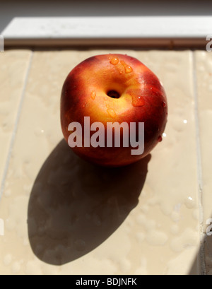 Nectarine fruit ripening in the sun on a windowsill fruit summer Stock Photo