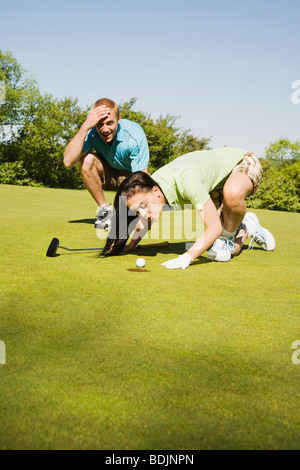 Golfer Trying to Blow Golf Ball Into Hole Stock Photo