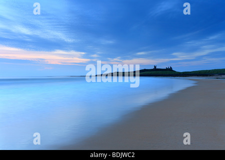 Dawn Embleton Bay, Dunstanburgh Castle on the horizon. Sunrise Northumberland coastal scene. Stock Photo