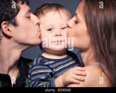 Family portrait. Mother and father kissing their son. Stock Photo
