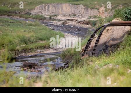 AN TAI BAO MINE, SHANXI PROVINCE, CHINA - AUGUST 2007: The stream passing by the vast open-caste mine is black with pollution Stock Photo