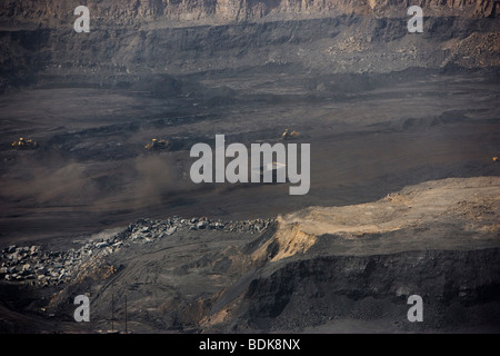 AN TAI BAO MINE, SHANXI PROVINCE, CHINA - AUGUST 2007: trucks throw up  dust as they collect coal from this vast open cast mine Stock Photo