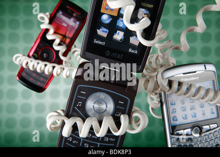 Cell phones floating on green background, wrapped with old fashioned coiled phone cord Stock Photo
