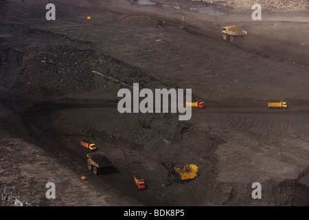 AN TAI BAO MINE, SHANXI PROVINCE, CHINA - AUGUST 2007: trucks throw up  dust as they collect coal from this vast open cast mine Stock Photo