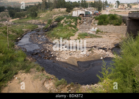 AN TAI BAO MINE, SHANXI PROVINCE, CHINA - AUGUST 2007: The stream passing by the vast open-caste mine is black with pollution Stock Photo