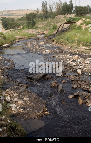 AN TAI BAO MINE, SHANXI PROVINCE, CHINA - AUGUST 2007: The stream passing by the vast open-caste mine is black with pollution Stock Photo