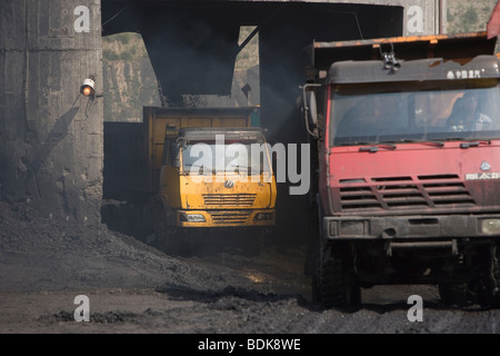 AN TAI BAO MINE, SHANXI PROVINCE, CHINA - AUGUST 2007: Road-going trucks fill up with coal from an overhead hopper. Stock Photo