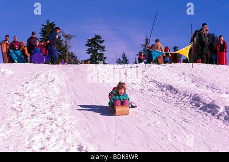 Children sledding on toboggan in Mount Seymour Provincial Park in 'Coast Mountains' North Vancouver British Columbia Columbia Stock Photo