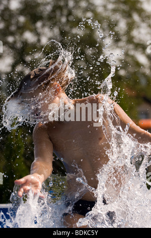 Teenage boy splashing around the water in the pool. Stock Photo