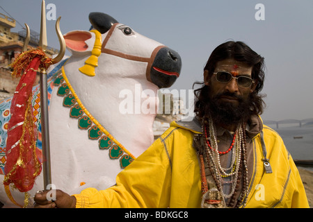 A Sadhu in the Indian city of Varanasi (Benares). He stands in front of a statue of Nandi, Shiva's vehicle.