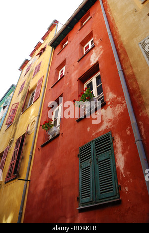 Many windows with various shutters on motley walls, dense building up old district of south town, view from bottom Stock Photo