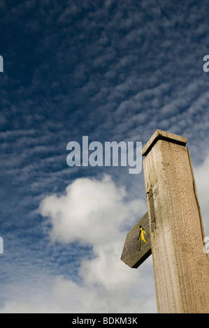 Public footpath signpost in front of Altocumulus undulatus and cumulus clouds Stock Photo