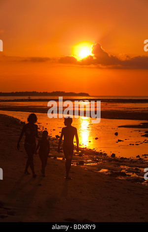 Indonesia, Lombok, Gili Air, north coast, sunset point, family walking along shore in setting sun Stock Photo