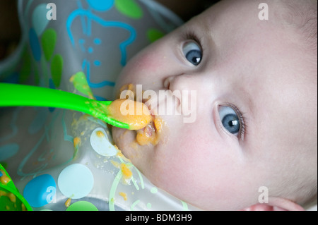 A toddler lying down eating food at meal time. Stock Photo