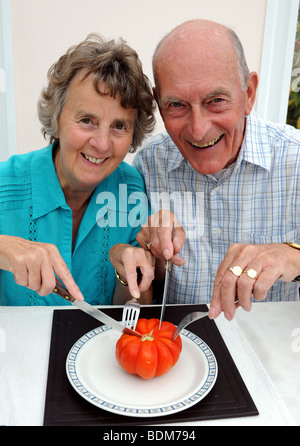 Couple who have grown a Big Tom variety of tomato weigh it on scales at 11 ounces Stock Photo