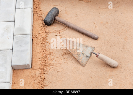 Tools of the mason on a sand surface - trowel and hammer Stock Photo
