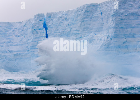 Big blue iceberg floating north in the Southern ocean near South Georgia Islands giant waves crashing against its' tall sides Stock Photo
