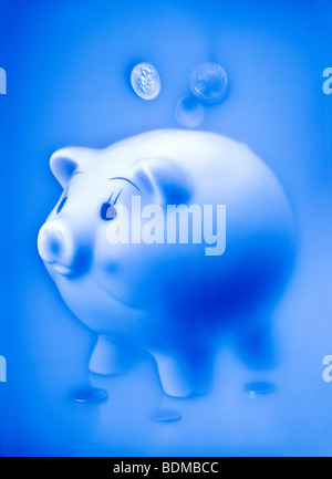 Conceptual image of coins falling from the sky into a piggy bank with a soft ethereal background and monochromatic Stock Photo