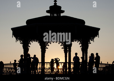 Silhouettes of people dancing cuban salsa on bandstand at sunset by sea, Hove, East Sussex, UK Stock Photo