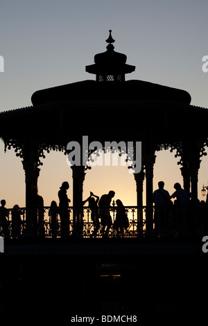 Silhouettes of people dancing cuban salsa on bandstand at sunset by sea, Hove, East Sussex, UK Stock Photo