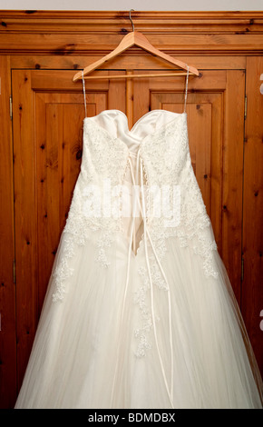 White wedding dress hanging on the outside of a wardrobe Stock Photo